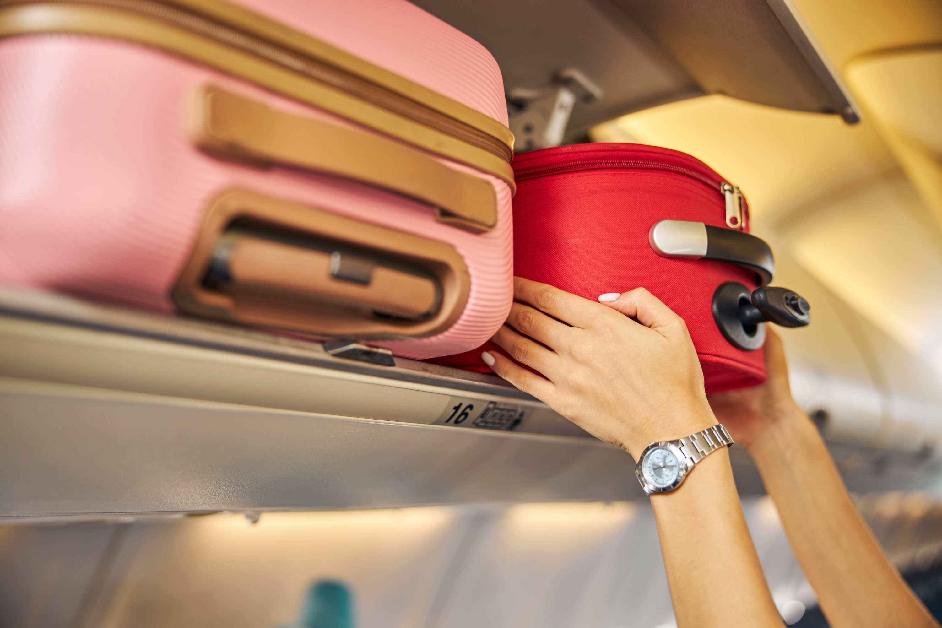 Hands laying down a carry on baggage on an upper shelf